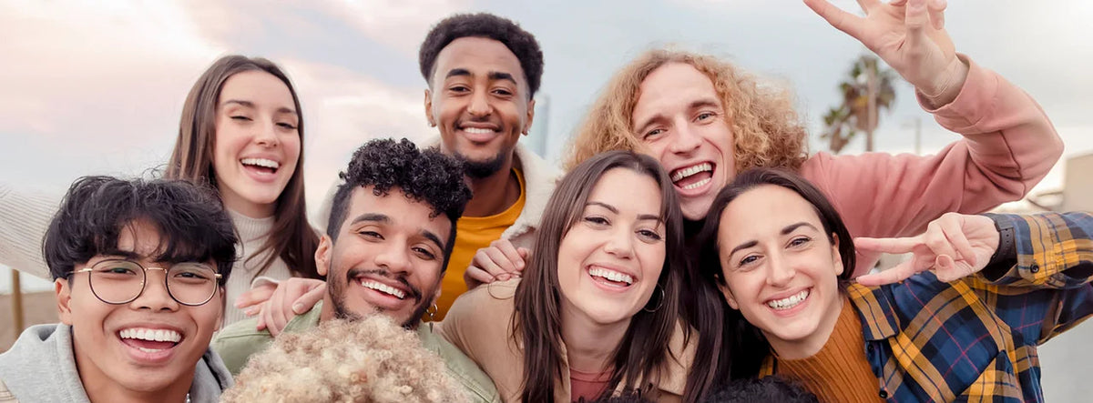 Group of seven smiling friends taking a selfie outdoors together, Robotime community lifestyle banner featuring diverse young crafters