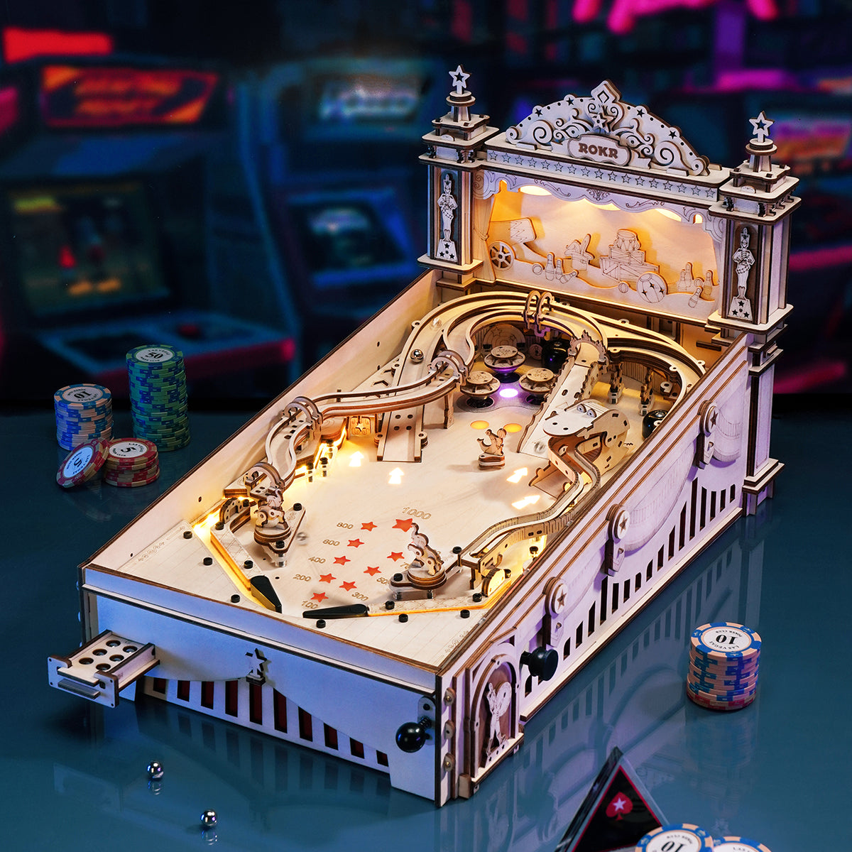 ROKR 3D Pinball Machine wooden puzzle assembled on gaming table with casino chips and cards in neon arcade ambiance