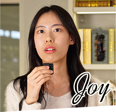 A Rolife team member named Joy holds a small black audio device while standing in a bookshelf-lined room with Rolife miniature displays in the background