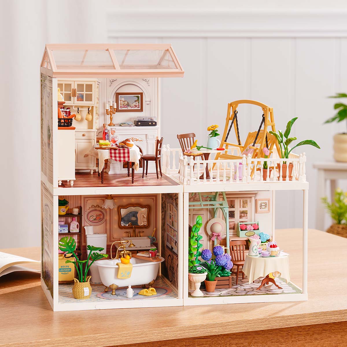 Rolife Super Creator Series 3-in-1 L Shape miniature with a dining room and rooftop terrace over a split lower level containing bathroom and garden tea room modules on a wooden desk.