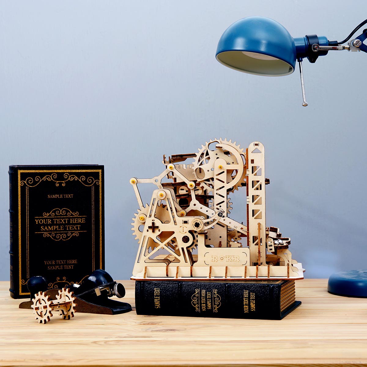 ROKR Marble Climber Fortress LG504 gear tower close-up on wooden desk beside blue desk lamp and books