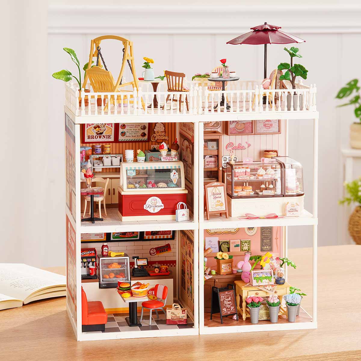 Rolife Super Creator Series 4-in-1 Four Grid wide six-room miniature with bedroom, garden cafe, yellow kitchen, living room, dining room, and bathroom in a horizontal white grid frame.