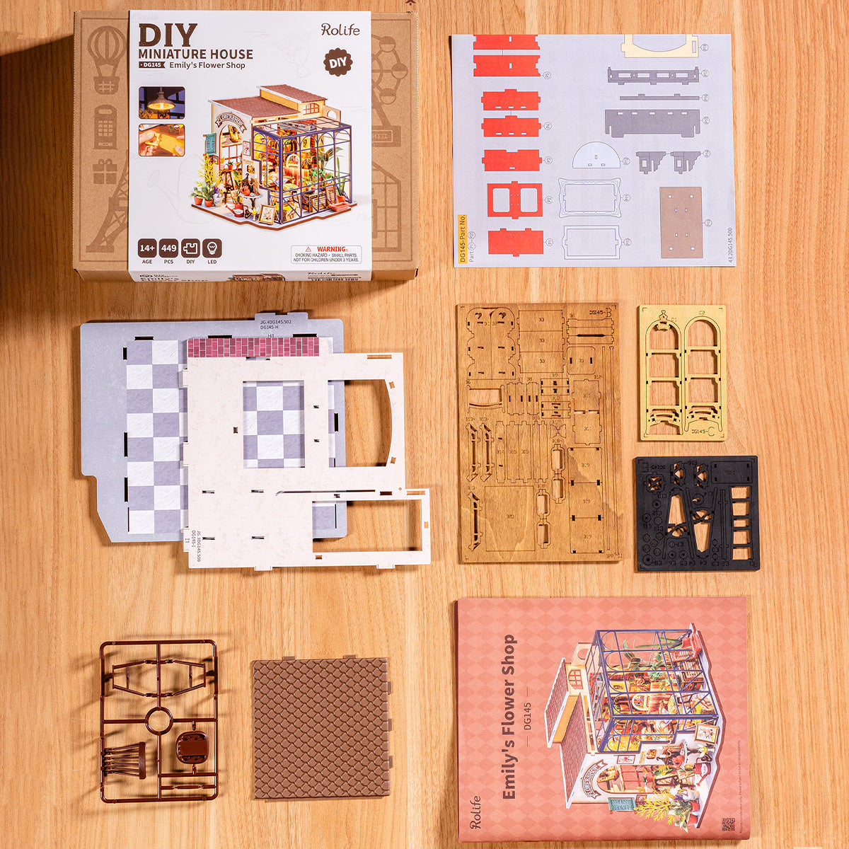 Rolife Emily's Flower Shop DG145 DIY miniature house flat lay showing box, laser-cut wooden boards and small accessory packs