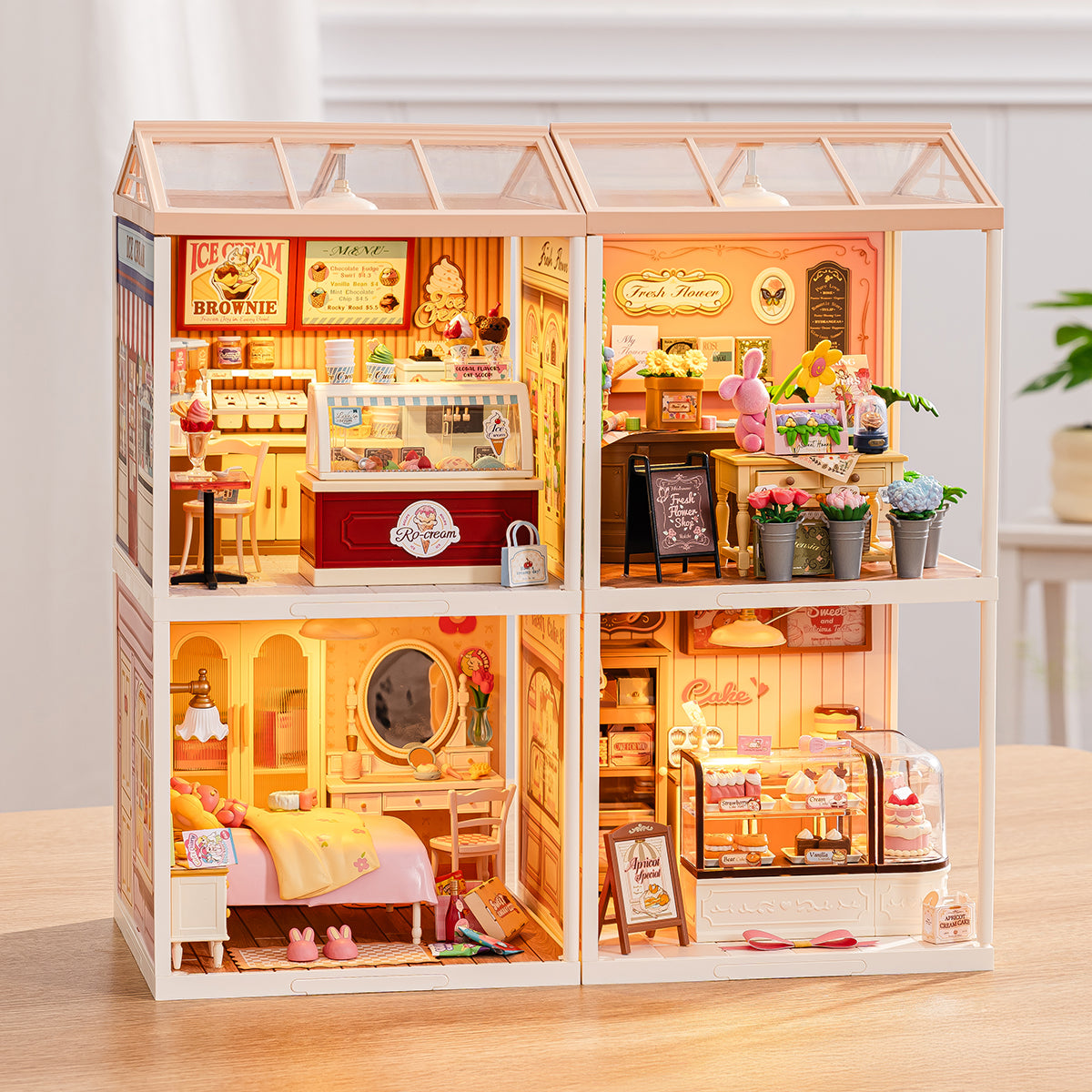 Rolife Super Creator 4-in-1 Four Grid illuminated DIY miniature house showing ice cream parlor, flower shop, bedroom and bakery scenes with warm LED glow