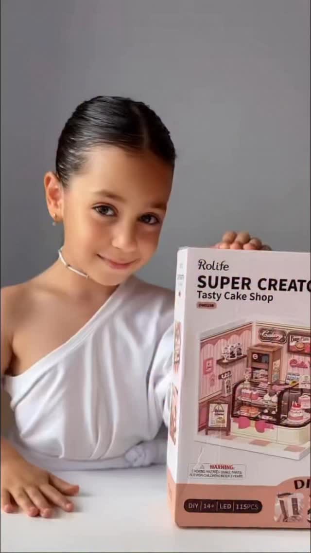 Fan smiling and holding a Rolife Fall Into Wonder TGB12 book nook alongside its retail packaging box with illustrated cover art