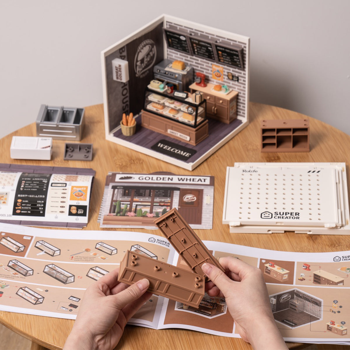 Rolife Golden Wheat Bakery DW005 DIY miniature house kit assembly scene with brown wall panels and instructions