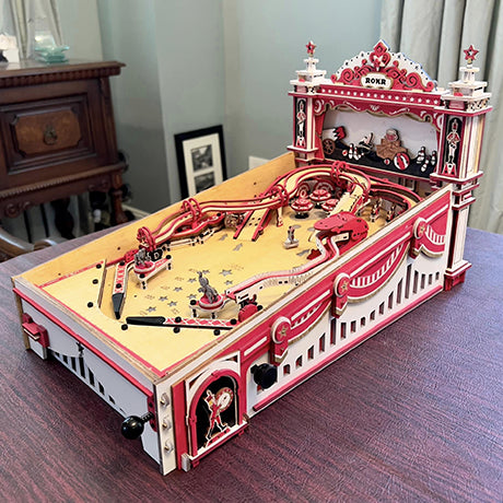 Robotime pink pinball table model shows ornate rails and miniature playfield details.