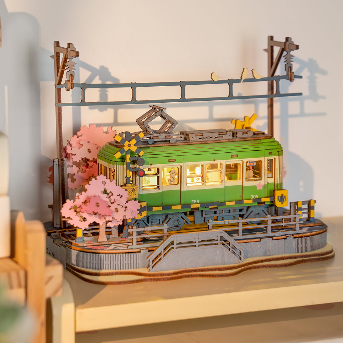 Rolife Sakura Journey TGS02 green tram scene with blooming sakura tree and wooden platform fence on shelf