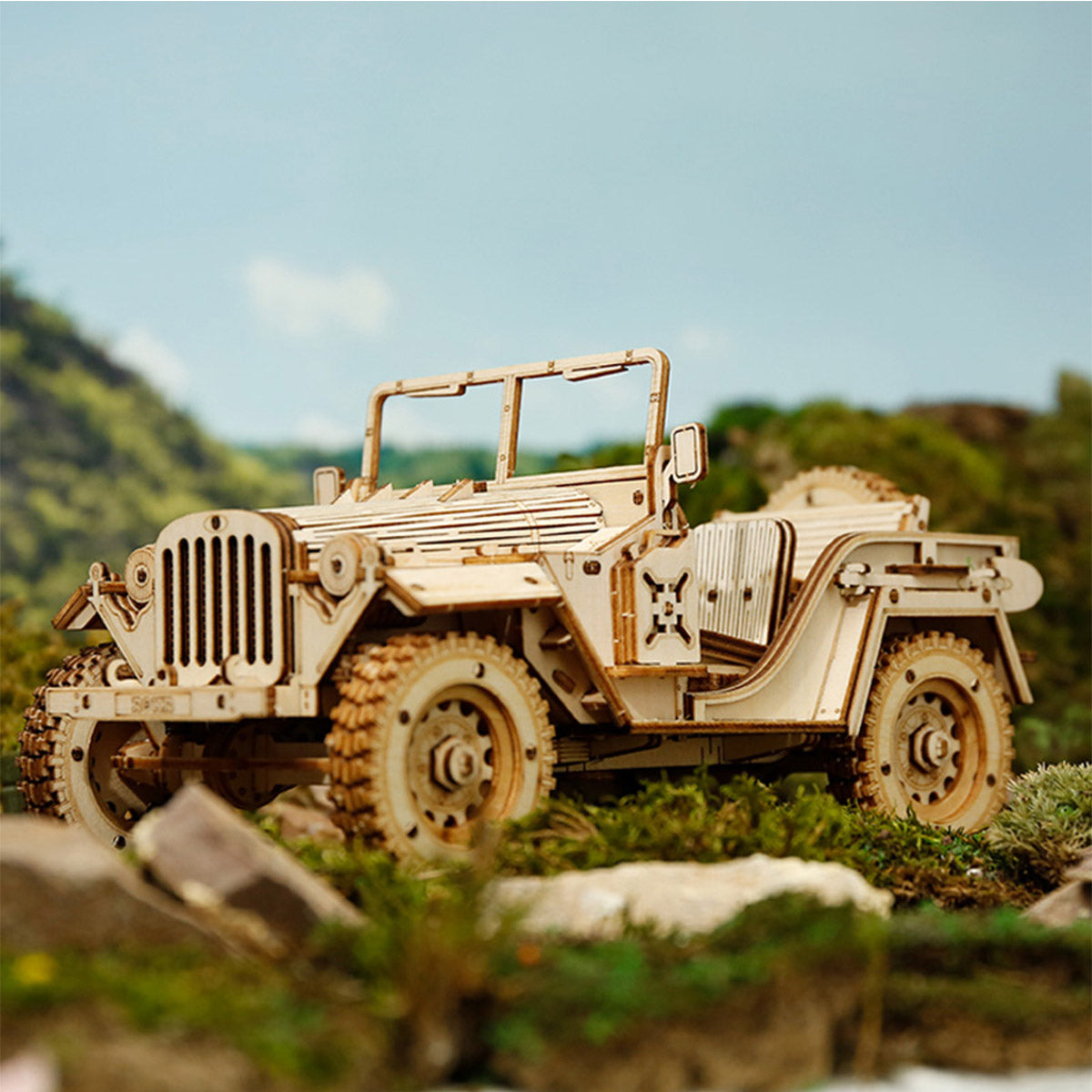 ROKR Army Jeep natural wood 3D puzzle model posed on mossy rocks with green hillside backdrop