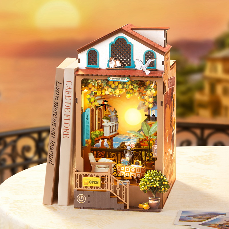 Rolife book nook kit featuring a sunny Mediterranean terrace scene with yellow flower vines, blue sky backdrop and terracotta building facade tucked between white books