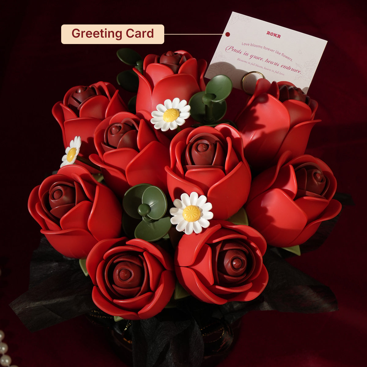 ROKR Red Rose Bouquet DIY kit AF02J assembled red rose bouquet in a black ROKR gift box with Best Wishes ribbon on a dark surface beside a real red rose and pearl bracelet