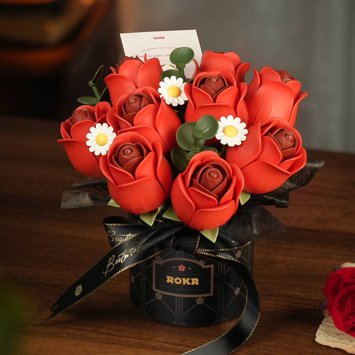 ROKR Red Rose Bouquet DIY kit AF02J fully assembled red rose arrangement in the black ROKR gift box with gold Best Wishes ribbon on a dark table beside a real red rose