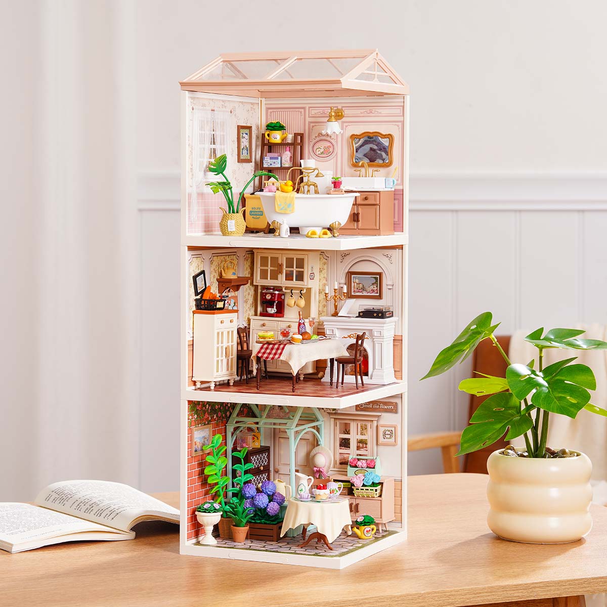 Rolife Super Creator Series 3-in-1 I Shape pink miniature tower with a bathroom on top, kitchen dining room in the middle, and garden tea room at the base on a white surface.