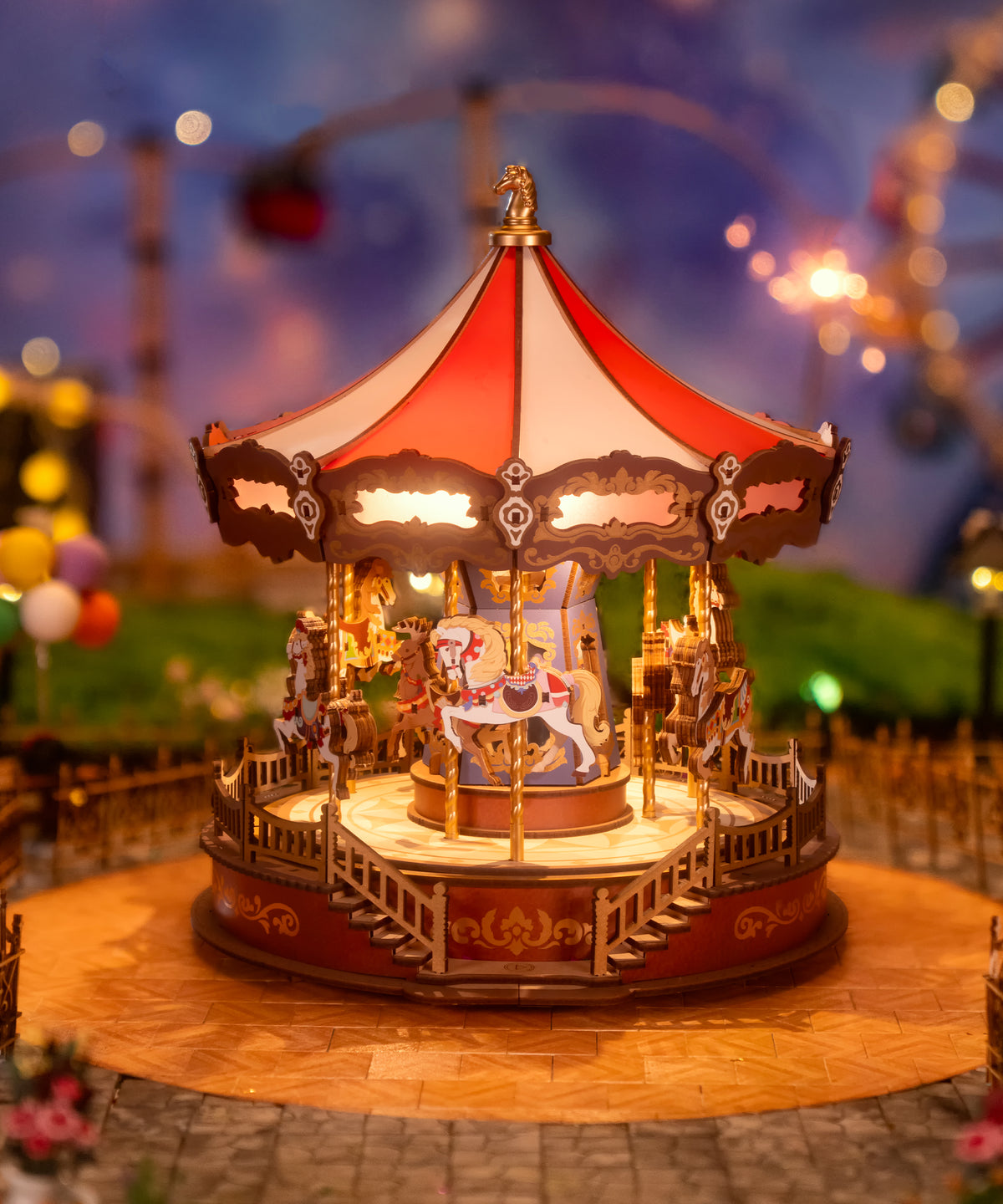 ROKR illuminated carousel wooden 3D puzzle glowing with warm lights and decorative horses displayed in a fairground scene at dusk.